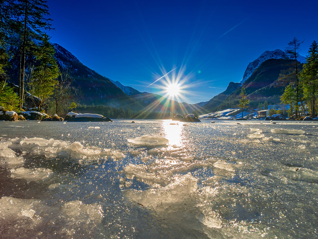 Zugefrorener Hintersee in Ramsau im Winterlicht, umgeben von verschneiten Bergen und Nadelwald – Winteridylle im Nationalpark Berchtesgaden.