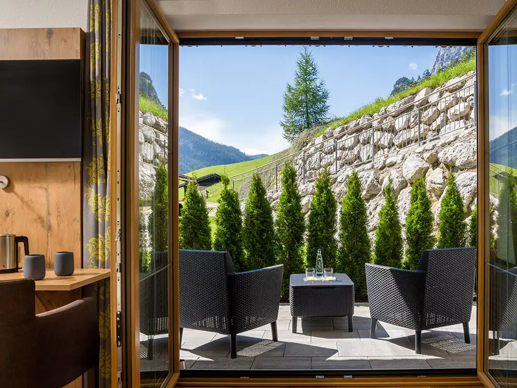 Blick in die Berchtesgadener Bergwelt von der Terrasse mit zwei Sesseln und Tisch, grüner Hecke – direkt zugänglich vom Zimmer im Wörndlhof.